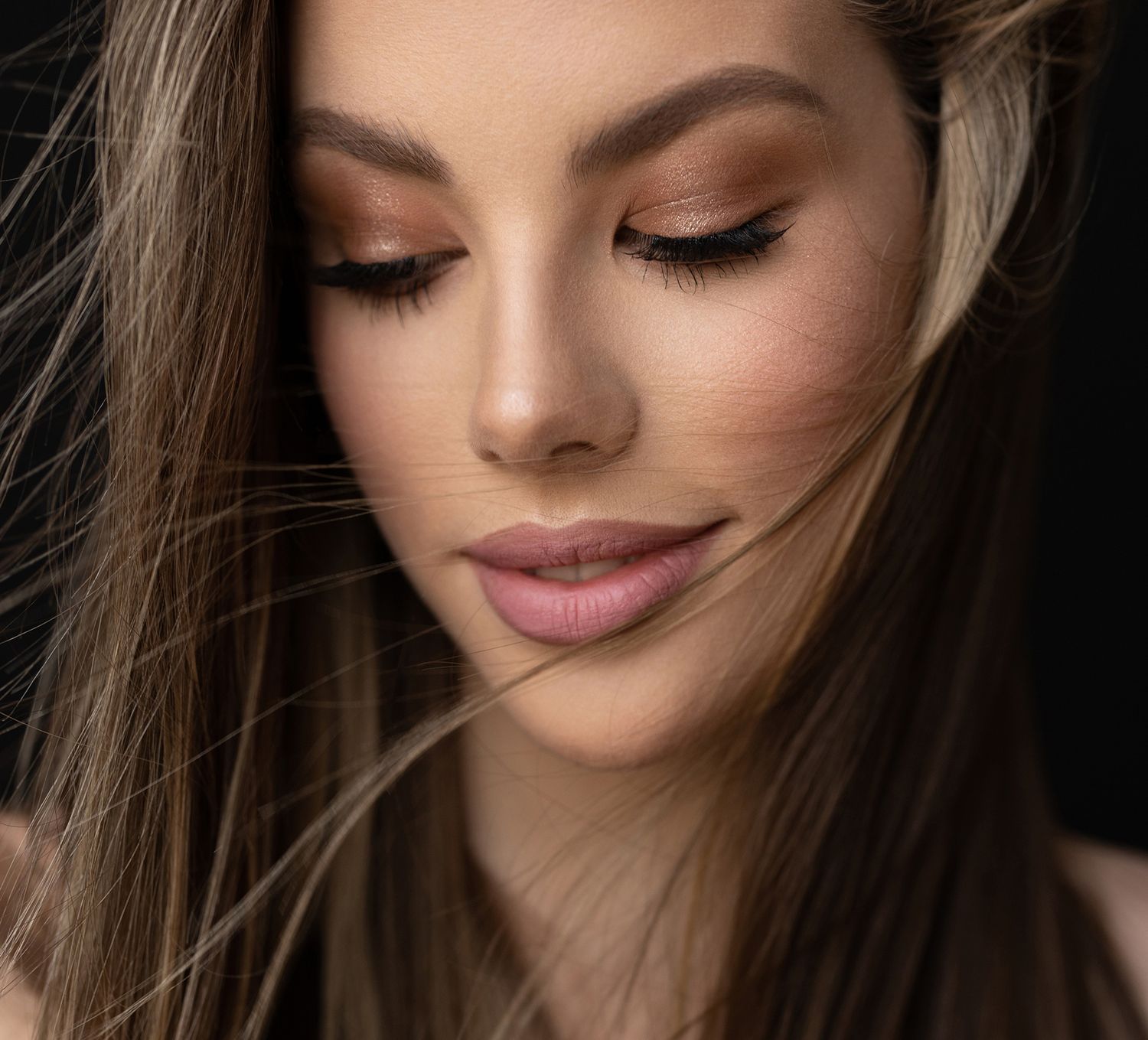 Close-up of woman with flowing hair and makeup.