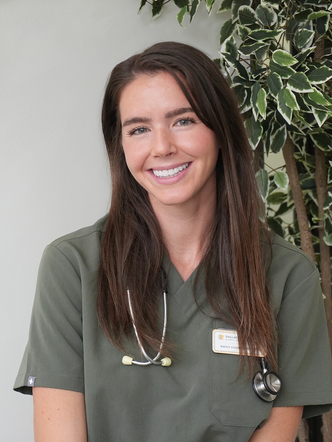 Woman smiling by a tree in green outfit.